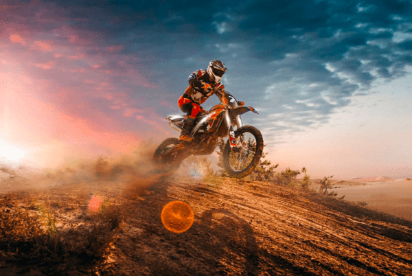 Motocross rider jumps dirt bike sunset.