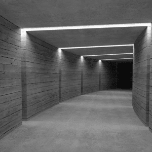 Lit concrete corridor leading to darkness.