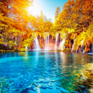 Autumn waterfall cascading into vibrant blue lake.