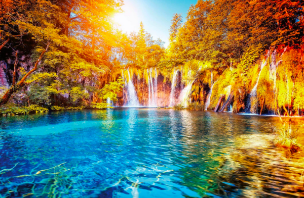 Autumn waterfall cascading into vibrant blue lake.