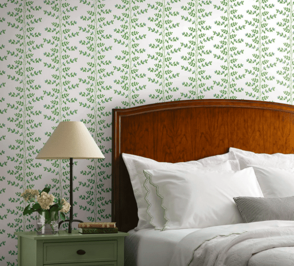 Green leafy wallpaper behind bed.