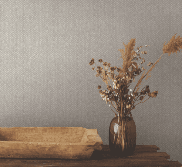 Dried flowers in vase, textured wall.